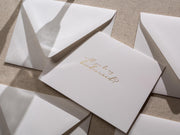 May include: A white card with gold foil lettering that says 'Will you be my bridesmaid?'